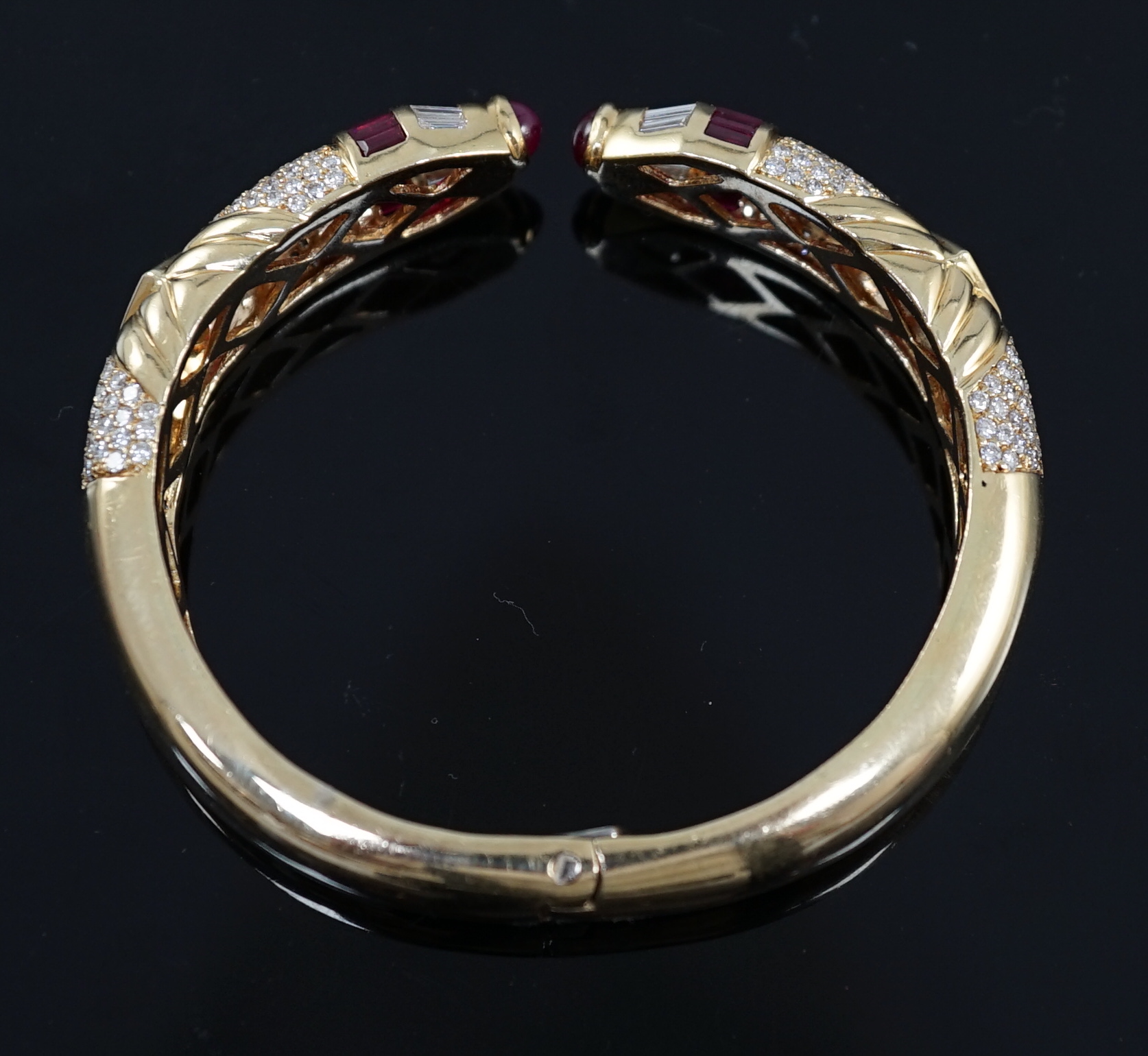 A modern 18ct gold, ruby and diamond cluster openwork hinged bangle